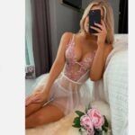 Woman sitting wearing white floral embroidered transparent lingerie with sheer mesh skirt