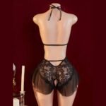 Back of a black lace teddy with a ribbon neck tie, slim horizontal straps, lower cutouts and mesh ruffles